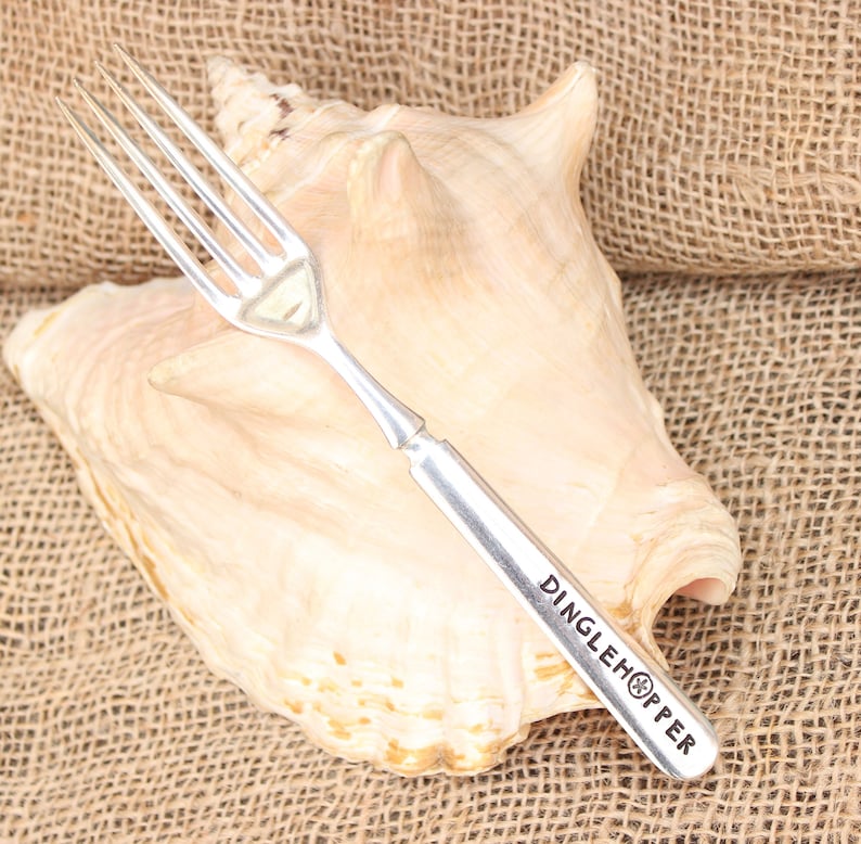 May include: Silver fork with a seashell design on the handle. The fork is engraved with the words "Dinglehopper".
