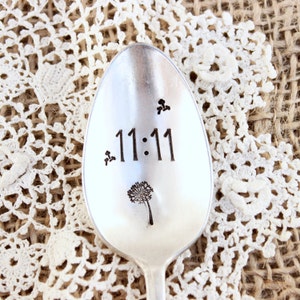 May include: A silver spoon with the number 11:11 engraved on it. The spoon also has a small dandelion design engraved on it.