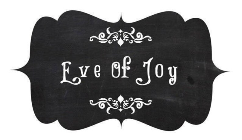 May include: A chalkboard-style sign with a black background and white text that reads "Eve of Joy." The sign has a decorative, ornate border at the top and bottom. The overall design is simple and elegant.