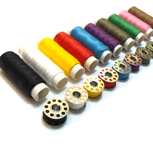 May include: A set of 12 spools of thread in various colors, including black, white, yellow, red, orange, blue, purple, green, brown, pink, and beige. The spools are arranged in a row, with the bobbins facing the viewer.