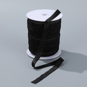 May include: A spool of black elastic trim with a white cardboard core. The elastic is wound tightly around the core and a length of the trim is hanging loose.
