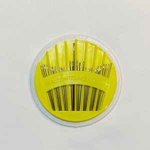 May include: A yellow plastic container with a clear lid holds 50 assorted needles. The container is round and has a scalloped edge. The text "50 ASSORTED NEEDLES" is printed on the container.