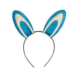 Puede incluir: Una diadema festiva con orejas de conejo azules y blancas brillantes. Las orejas son de un azul vibrante con una secci&oacute;n interior blanca y est&aacute;n unidas a una diadema de pl&aacute;stico negro. Perfecta para celebraciones de Pascua o fiestas de disfraces.