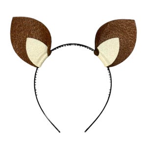 May include: A brown and white felt headband with deer ears. The headband is black and has a simple design.