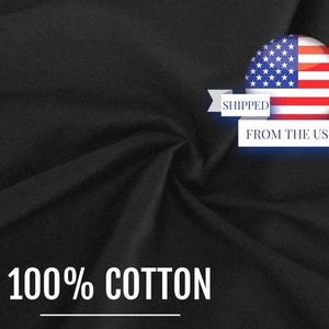 May include: A solid black fabric with a soft, draped texture. The image features a circular graphic of the United States flag with a white banner containing the text SHIPPED FROM THE USA. The text 100% COTTON is printed in white at the bottom.