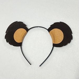 May include: A brown headband with two fuzzy brown ears with tan inner ears. The headband is made of black plastic.