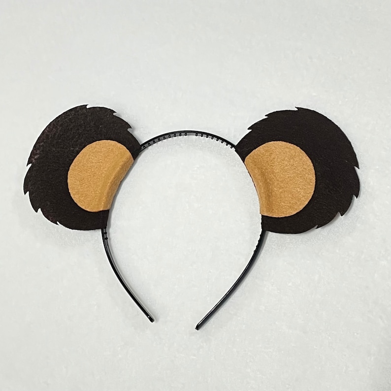 May include: A brown headband with two fuzzy brown ears with tan inner ears. The headband is made of black plastic.