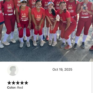 Puede incluir: Un grupo de personas con uniformes de softbol rojos y diademas con orejas de conejo. Los uniformes tienen un logotipo. El equipo est&aacute; al aire libre en un d&iacute;a soleado.