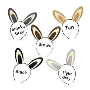 Puede incluir: Cinco diademas de orejas de conejo en varios colores: gris humo, marr&oacute;n claro, marr&oacute;n, negro y gris claro. Cada diadema tiene una fina montura de alambre negro y el nombre del color impreso en un c&iacute;rculo blanco.