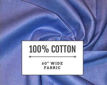 May include: A solid periwinkle blue fabric with a smooth texture, featuring a white rectangular overlay with black text that reads 100% COTTON and 60" WIDE FABRIC, separated by a horizontal line with diamond-shaped ends at the center.