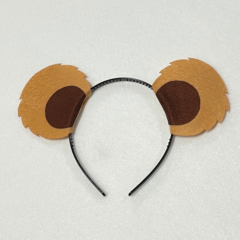 May include: A brown and black headband with fuzzy ears. The ears are shaped like a bear's ears with a brown inner circle.