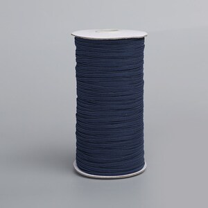 May include: A spool of dark blue elastic cord, wound around a white cardboard core.