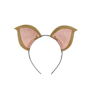 May include: A headband featuring two stylized animal ears. The ears have a gold trim and a pink interior. The headband itself is black and thin, designed to be worn on the head. The ears are symmetrical and stand upright.