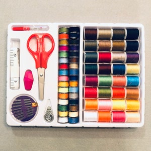 May include: A white plastic sewing kit with a variety of colorful threads, a pair of scissors, a needle threader, and a small ruler. The kit includes 24 spools of thread in different colors.