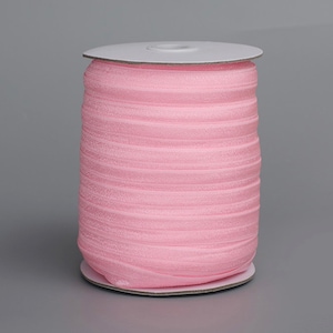 May include: A spool of pink elastic fold over elastic, also known as FOE, for sewing and crafting projects.