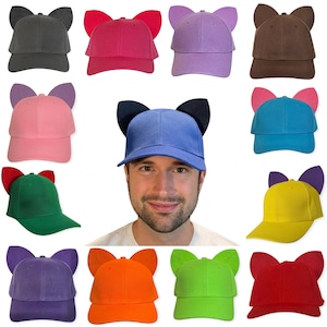 May include: A collection of twelve baseball caps in various solid colors, each featuring two upright cat ears attached to the crown. The colors include black, hot pink, lavender, brown, light pink, blue, green, yellow, purple, orange, lime green, and red.