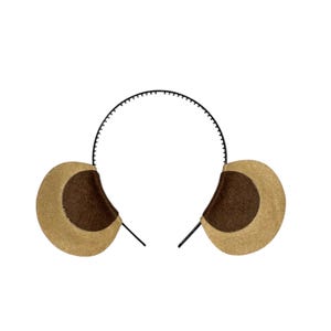 May include: A headband with two plush bear ears. The ears are tan with a dark brown center. The headband is black and has small teeth-like details along the top.