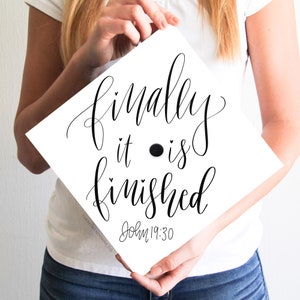 以下が含まれることがあります： 白い卒業帽に、黒い書体で「ついに終わった ヨハネ 19:30」と書かれている。