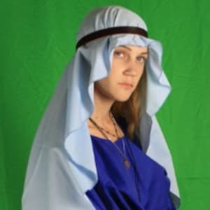 Op de afbeelding: Een vrouw draagt een blauwe robe met een lichtblauwe hoofdbedekking. De robe heeft lange mouwen en een getailleerde taille. De hoofdbedekking is over haar hoofd en schouders gedrapeerd.