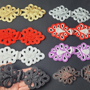 May include: Assortment of 10 decorative Chinese knot buttons in various colors, including gold, red, white, purple, black, and brown. The knots are intricately woven and feature a traditional design.