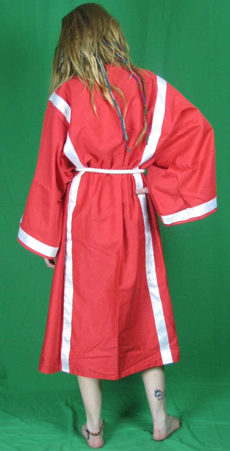 May include: A red robe with white trim and a white rope belt. The robe has long sleeves and a loose fit. The person wearing the robe has long, blonde hair with blue and green streaks.