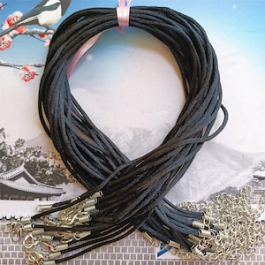 May include: A bundle of black cord necklaces with silver lobster clasps. The cords are arranged in a circle and are ready to be used for jewelry making.