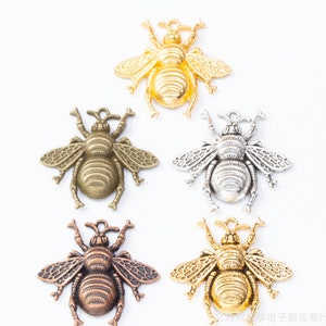 Puede incluir: Cinco abalorios de abeja de metal en diferentes colores: oro, plata, bronce y dos tonos de oro. Las abejas tienen alas y cuerpos detallados.