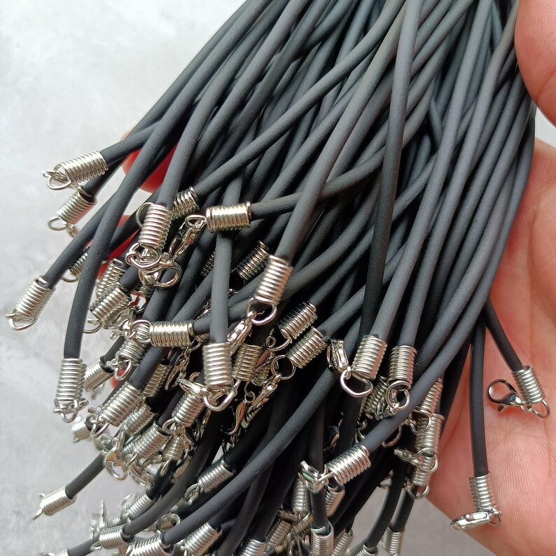 Puede incluir: Un manojo de m&uacute;ltiples collares de cord&oacute;n de caucho negro, cada uno con un terminal de resorte de metal plateado y un cierre de langosta. Los cordones son lisos, flexibles y de grosor uniforme, dise&ntilde;ados para la creaci&oacute;n de joyer&iacute;a.