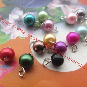 May include: Assortment of colourful pearl beads with silver loops. The beads are in various colours, including red, green, blue, purple, pink, and black.