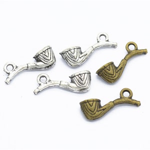 Op de afbeelding: Vijf zilveren en bronzen pijpbedels. De bedels zijn gedetailleerd met een textuurontwerp en hebben een lus om aan een ketting of armband te bevestigen.