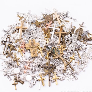 May include: A large collection of silver and gold-toned metal cross charms. The charms are of various sizes and styles, including simple crosses, ornate crosses, and crosses with decorative details.