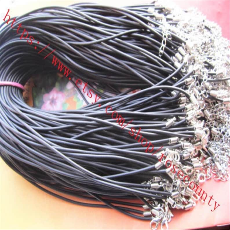 Puede incluir: Un gran paquete de collares de cord&oacute;n negro, cada uno con un cierre de metal plateado y una cadena de extensi&oacute;n ajustable. Los cordones son lisos y flexibles, reunidos en una bobina densa con los herrajes met&aacute;licos agrupados en un extremo.