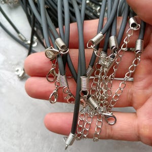 Puede incluir: Una colecci&oacute;n de cordones negros de caucho para collares con terminales met&aacute;licos de tono plateado, cierres de mosquet&oacute;n y cadenas extensoras ajustables. Estos cordones est&aacute;n dise&ntilde;ados para la creaci&oacute;n de joyer&iacute;a y sirven de base.