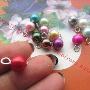 May include: Assortment of colourful pearl beads with silver loops. The beads are in various colours, including pink, red, purple, green, and white.