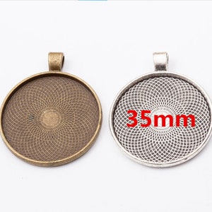 May include: Two round metal pendant trays with a decorative pattern. The tray on the left is bronze and the tray on the right is silver. Both trays have a loop at the top for hanging and measure 35mm in diameter.