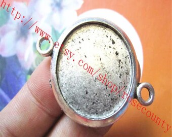 May include: Silver-toned round pendant with a smooth, circular surface and two loops for attaching a chain or cord. The pendant is designed to hold a round cabochon.