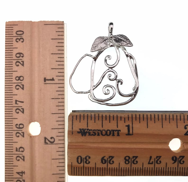 Puede incluir: Encanto de plata en forma de pera con un dise&ntilde;o de espiral y hojas. El encanto mide aproximadamente 2,5 cm de largo. El encanto se mide contra una regla.