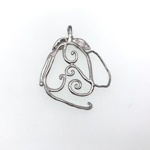 Puede incluir: Un colgante de plata en forma de pera con un dise&ntilde;o de espiral.