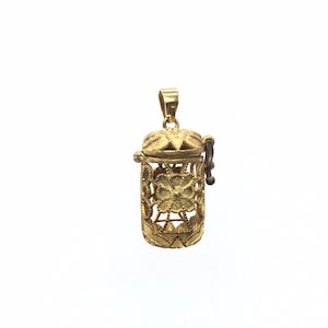 May include: A gold filigree locket pendant with a hinged lid and a small handle. The locket is intricately designed with floral patterns and has a delicate, ornate look.