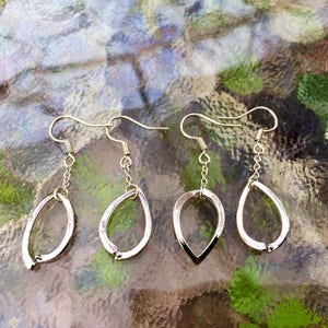 Op de afbeelding: Een set van drie paar zilveren oorhangers. Elke oorbel heeft een traanvormig ontwerp met een gladde, gepolijste afwerking.