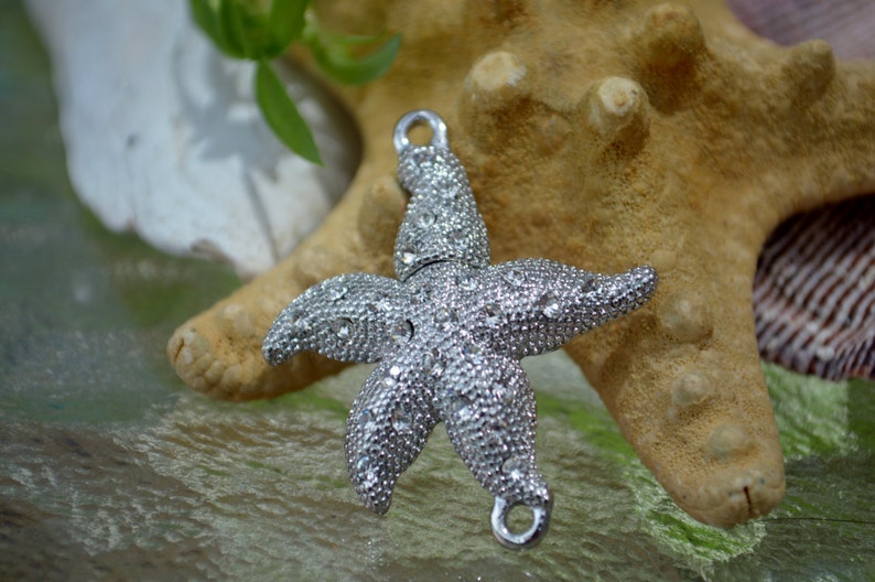 May include: A silver starfish charm with rhinestones, perfect for jewelry making or crafting projects.