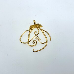 Puede incluir: Un colgante de color dorado en forma de pera con un dise&ntilde;o de espiral y dos peque&ntilde;as hojas.