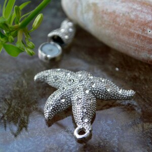 May include: A silver starfish charm with rhinestones, perfect for jewelry making or crafting projects.