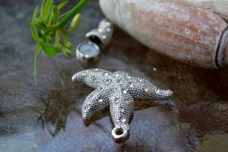 May include: A silver starfish charm with rhinestones, perfect for jewelry making or crafting projects.