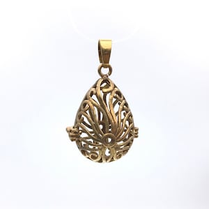 May include: A gold-toned metal pendant in the shape of a teardrop with an intricate, openwork design. The pendant is designed to be a charm or ornament.