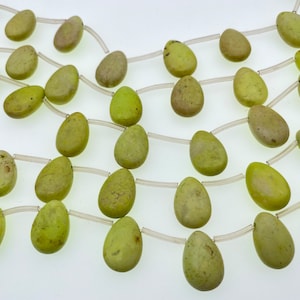Puede incluir: Una hebra de cuentas de piedras preciosas de color verde claro, cada cuenta tiene forma de lágrima, enhebrada en un cordón elástico transparente.