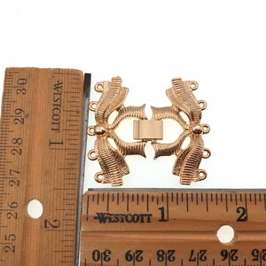 K&ouml;nnte beinhalten: Vergoldeter Metallverschluss mit dekorativem Design, etwa 2,5 cm lang. Der Verschluss hat mehrere Schlaufen zum Anbringen von Schmuck oder anderen Gegenst&auml;nden.