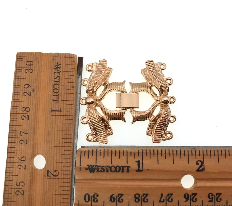 K&ouml;nnte beinhalten: Vergoldeter Metallverschluss mit dekorativem Design, etwa 2,5 cm lang. Der Verschluss hat mehrere Schlaufen zum Anbringen von Schmuck oder anderen Gegenst&auml;nden.