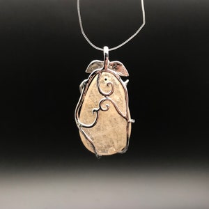 Puede incluir: Un colgante de plata con una piedra transparente en forma de pera engastada en un delicado dise&ntilde;o de alambre en espiral.