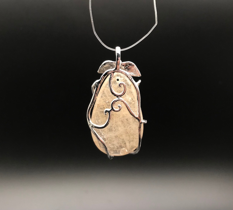 Puede incluir: Un colgante de plata con una piedra transparente en forma de pera engastada en un delicado dise&ntilde;o de alambre en espiral.